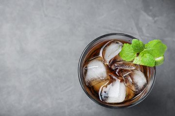 Glass of Rum and Cola cocktail on grey stone table, top view. Space for text