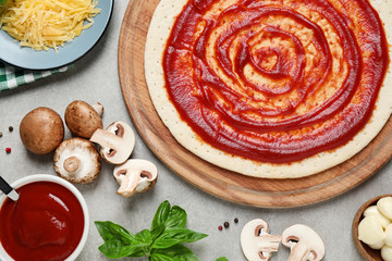 Flat lay composition with pizza crust and ingredients on grey table, closeup