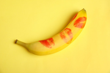 Fresh banana with red lipstick marks on yellow background. Oral sex concept