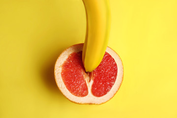 Fresh grapefruit and banana on yellow background, top view. Sex concept