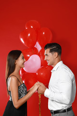 Beautiful couple with heart shaped balloons on red background