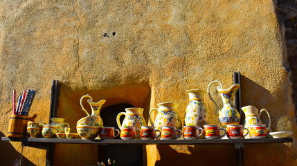 Variety of handmade painted clay pieces like cups, bowls, plates and large trays for sale in...