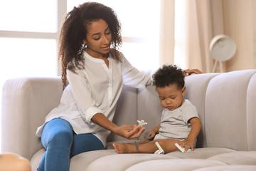 Obraz premium African-American woman with her baby in living room. Happiness of motherhood