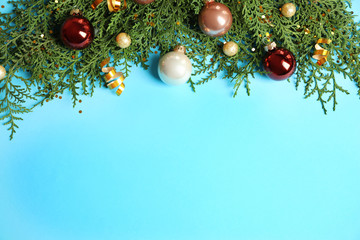 Fir tree branches with Christmas decoration on light blue background, flat lay. Space for text
