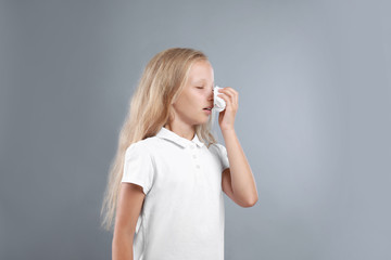 Little girl suffering from allergy on grey background