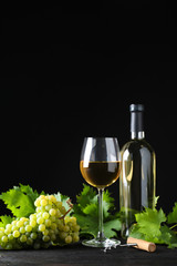 Fresh ripe juicy grapes with wineglass on grey table against black background, space for text