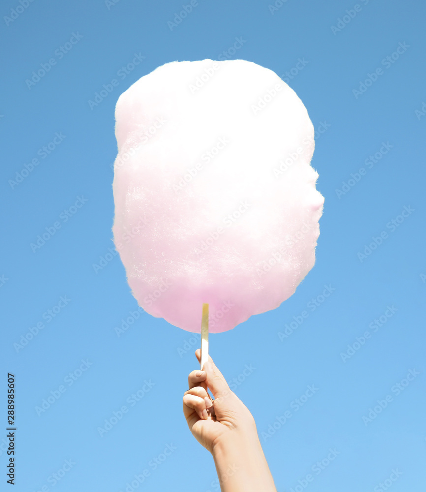 Wall mural Woman holding white cotton candy against blue sky