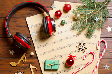 Flat lay composition with Christmas decorations, headphones and music sheets on wooden table