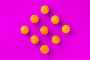 Fruit pattern of fresh orange tangerine or mandarin on lilac background. Flat lay, top view. Pop art design, creative summer concept. Citrus in minimal style.