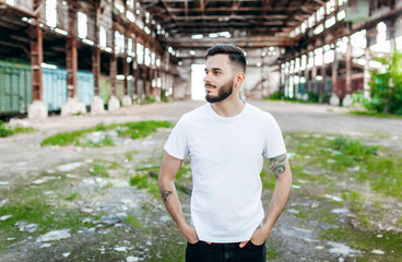A young stylish man with a beard in a white T-shirt and glasses. Street photo