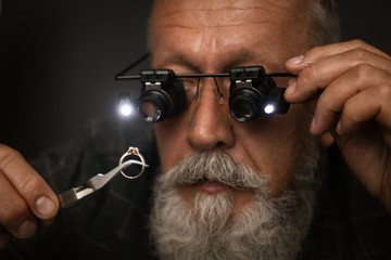 Male jeweler evaluating diamond ring in workshop, closeup view - obrazy, fototapety, plakaty
