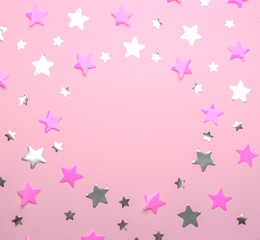 Frame made of confetti stars with space for text on pink background, top view. Christmas celebration