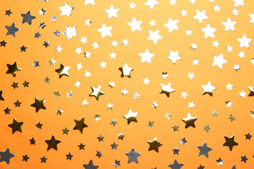 Confetti stars on orange background, flat lay. Christmas celebration