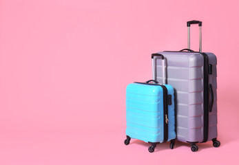 Modern suitcases on light pink background. Space for text