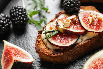 Bruschettas with cream cheese, figs and blackberries on slate plate, closeup