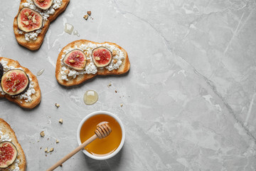 Bruschettas with cheese, figs and honey on marble table, flat lay. Space for text