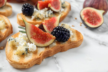 Bruschettas with cheese, figs and blackberries served on white table, closeup