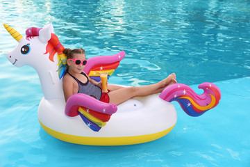 Happy little girl on inflatable unicorn in swimming pool © New Africa