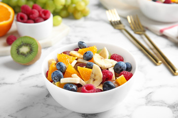 Fresh tasty fruit salad on white marble table