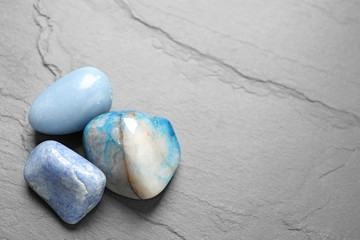 Fototapeta na wymiar Beautiful natural blue gemstones on grey table, space for text