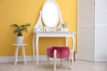 Stylish room interior with modern dressing table near yellow wall