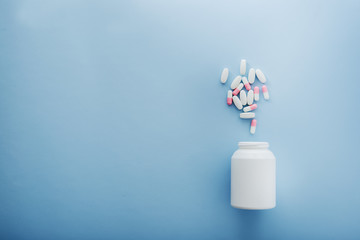 Pharmaceutical medicine pills and bottle on blue background.