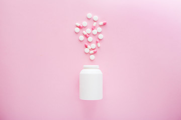 Heap of white and pink pills on pink background.