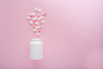 Fototapeta na wymiar Heap of white and pink pills on pink background.