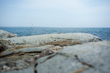 Obraz premium Sailboat in distance with rocks in foreground