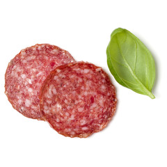 Slices of salami isolated on white background closeup. Sausage and basil leaves top view.
