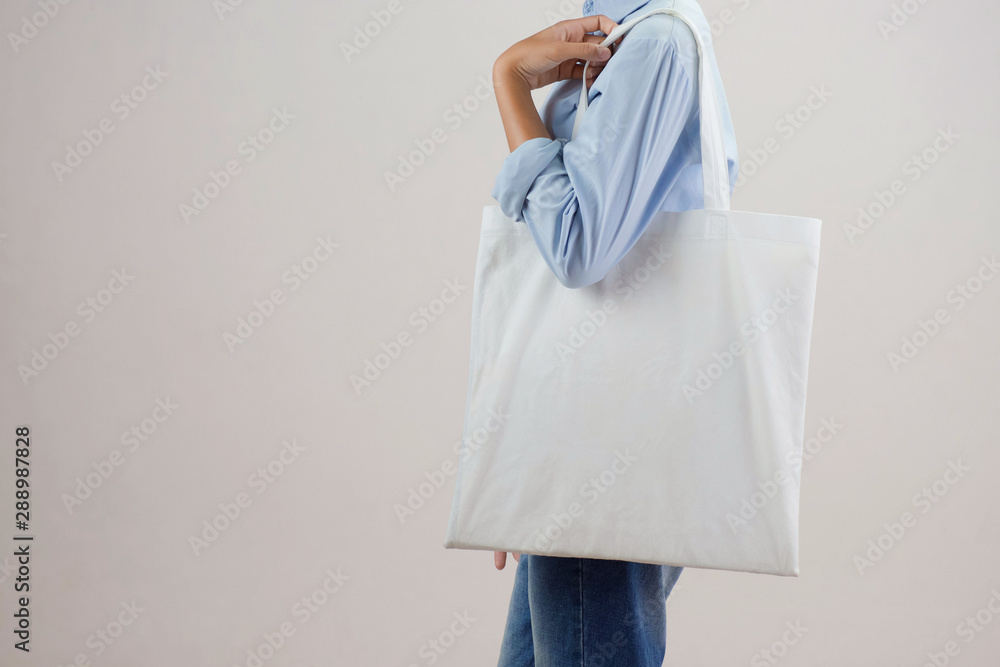 Wall mural young woman holding eco cotton bag on white background