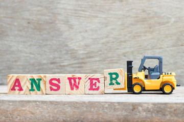 Toy forklift hold letter block r to complete word answer on wood background