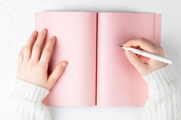 pink notebook with empty sheet on a white background with pen in hands