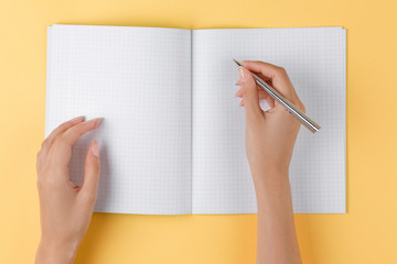 girl writes in an open notebook top view, yellow background
