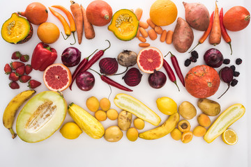 top view of assorted raw colorful autumn vegetables, berries and fruit on white background