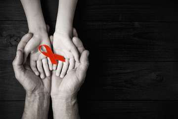 AID red ribbon in hand on a black wooden background.black and white.