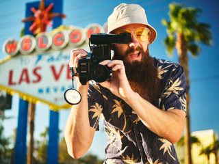 retro tourist in vegas with 80s camcorder in front of sign