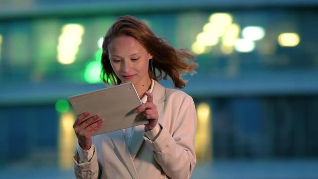Businesswoman using electronic tab outdoors in the evening.