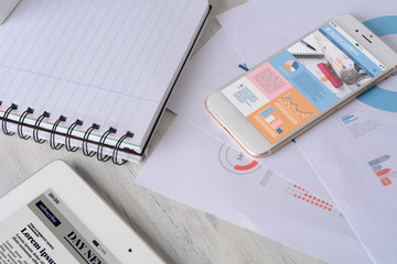 Spiral notepad, financial papers and smartphone with statistics about company growth