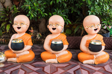 Novices carrying a bowl Statue of novice monks in temple Thailand Buddhist.