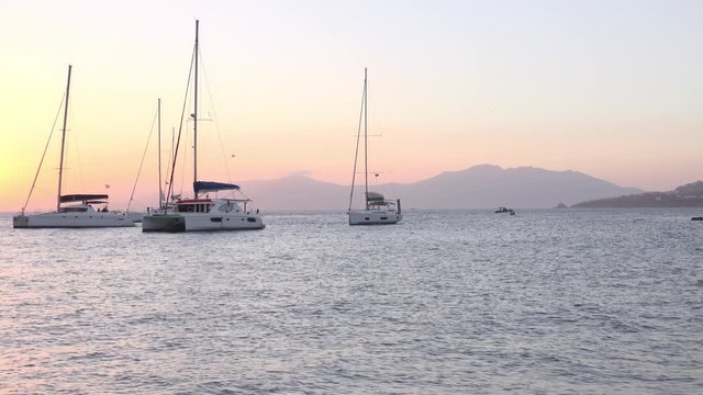 Panoramic view of Mykonos town harbour. Romantic colorful sunset on Little Venice, Cyclades islands. Yachts on evening Aegean sea and mountains on background. Amazing touristic place, Alefkandra area