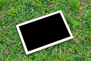 Mock up image of a blackboard put on the green grass field floor background.