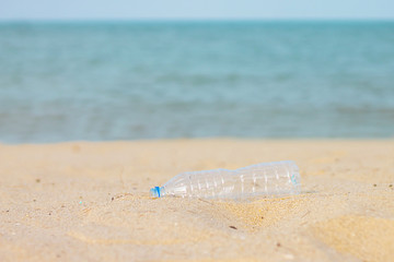 Fototapeta na wymiar A​ plastic bottle on​ the​ sand beach at​ the​ sea.​ Pollution and​ environmental​ save​ concept.
