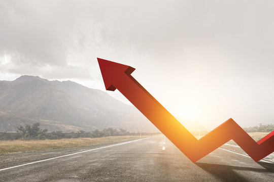 Orange zigzag increasing arrow standing on highway against mountain landscape background