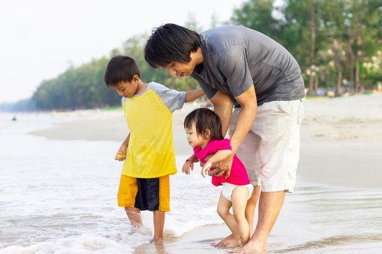 Portrait image of Asian Farther with children son and daughter playing on the beach at the sea. Summer season. Father's day and family concept.