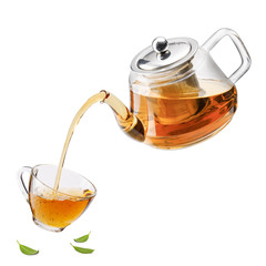 Jug pouring hot tea into glass cup with green tea leaves in the air, Healthy products by organic...