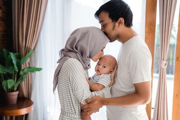 muslim parent kissing together with baby boy at home