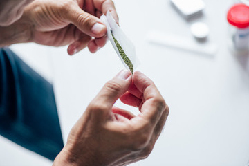 cropped view of man rolling blunt with medical cannabis