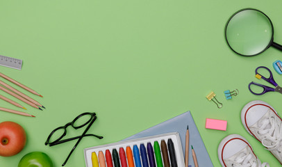 Creative flatlay of education green table with student books, shoes, colorful crayon, eye glasses, empty space isolated on green background, Concept of education and back to school
