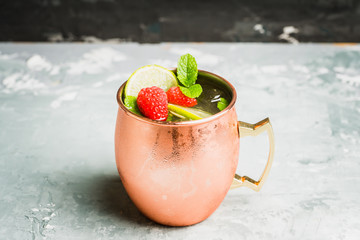 Raspberry and lime cocktail in copper mug (variation of Moscow mule) on the rustic background. Selective focus. Shallow depth of field.